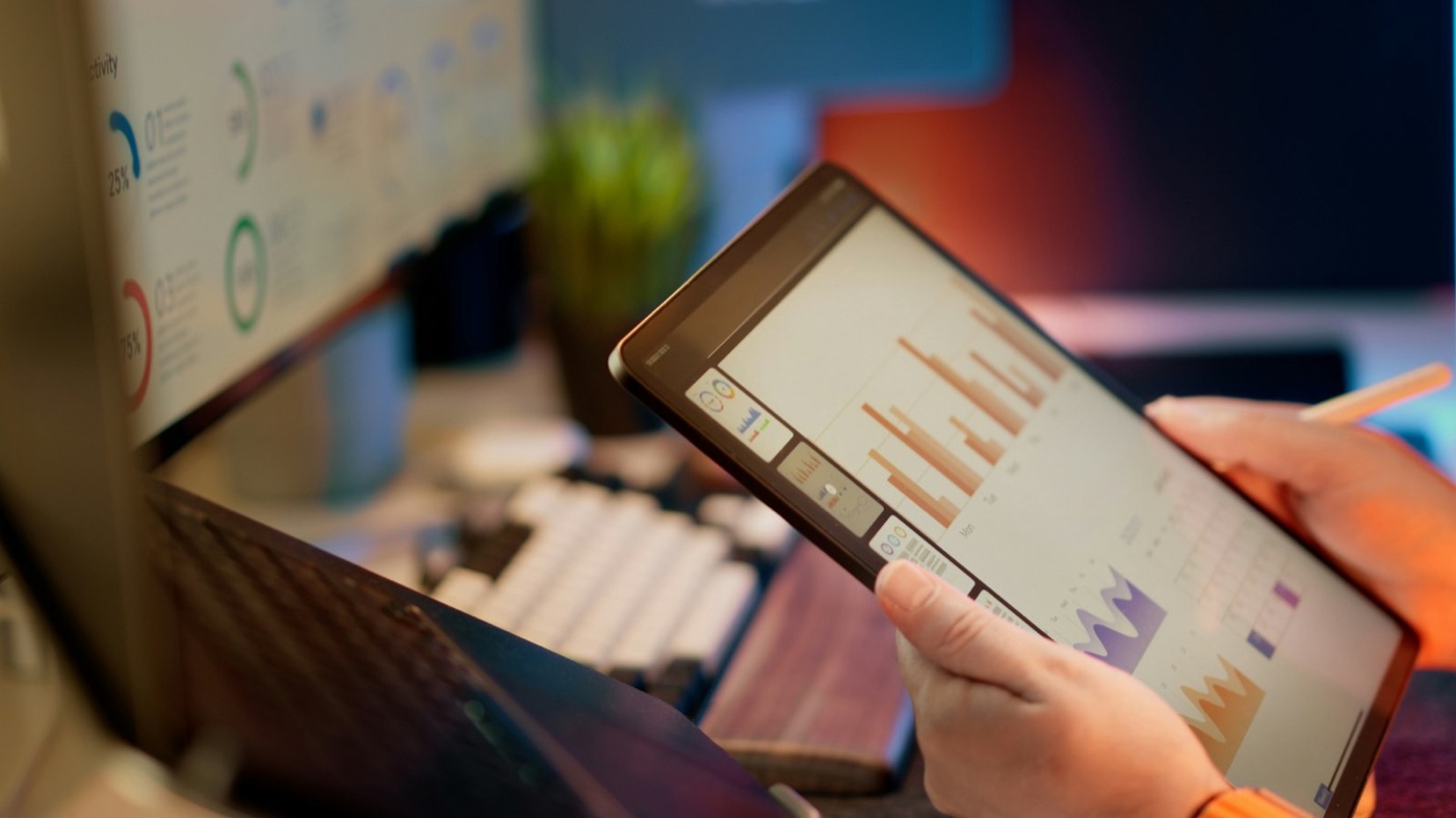 Tablet showing business growth analytics in front of data dashboards